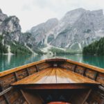 Virtual Travel - brown wooden boat moving towards the mountain