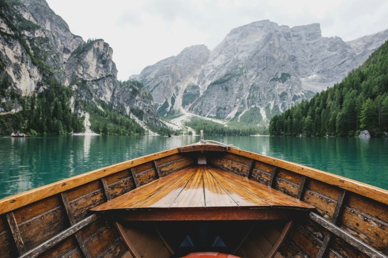 Virtual Travel - brown wooden boat moving towards the mountain
