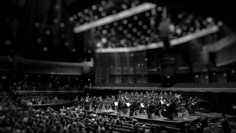 Quantum Vs Classical - grayscale photography of orchestra playing on theatre