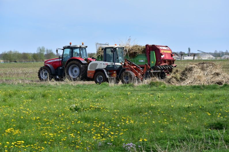Agricultural Automation - a red tractor pulling a trailer of hay through a field
