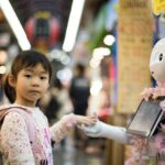 Robot Handshake - photo of girl laying left hand on white digital robot