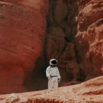 Mars Habitat - photography of astronaut standing beside rock formation during daytime