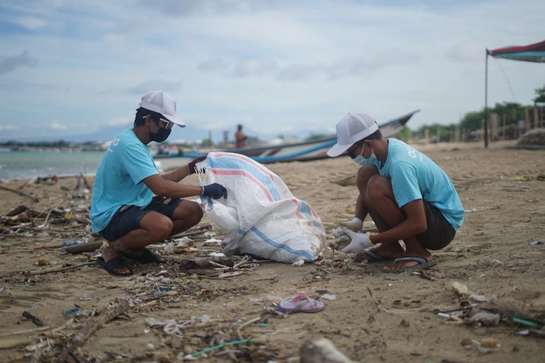 Ocean Cleanup - man in blue shirt sitting on sand during daytime